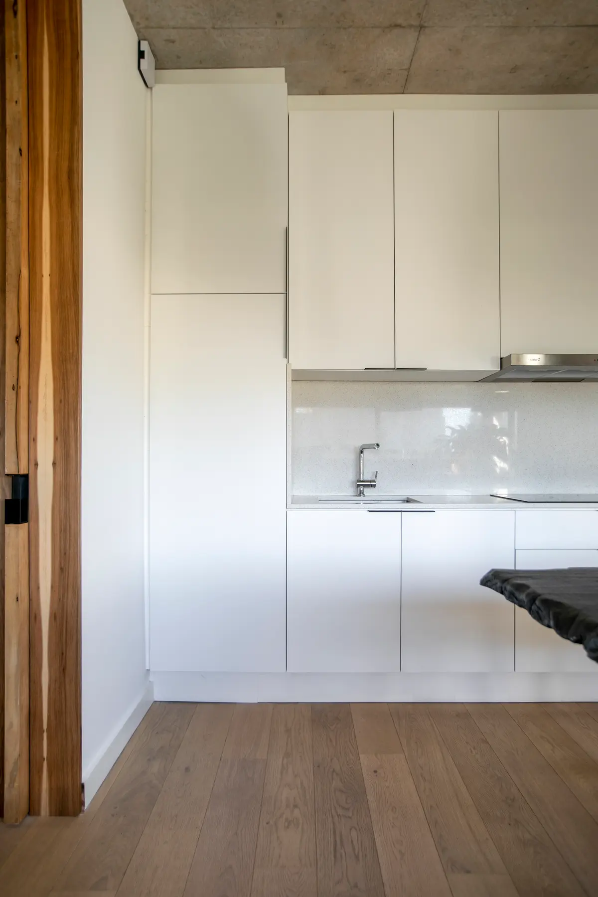 Cozinha branca minimalista com detalhes em madeira e concreto — projeto Gray Rock, por BAS Y GARCIA, em Escobar
